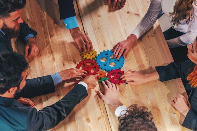 Il team aziendale collega pezzi di ingranaggi colorati come un lavoro di squadra e partner