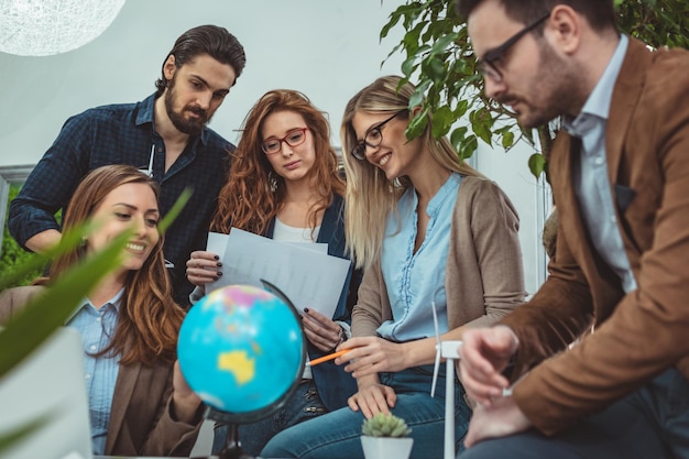 Il team aziendale sta discutendo di nuovi mercati, guardando un globo e discutendo di informazioni di mercato globali.