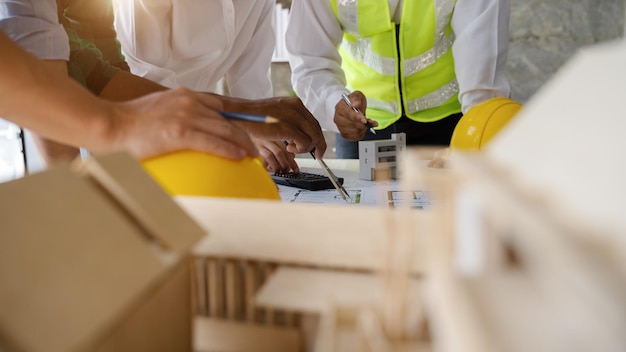 Il team di architetti o ingegneri che lavora al tavolo utilizza lo strumento di disegno sul piano cartaceo per il progetto architettonico aziendale