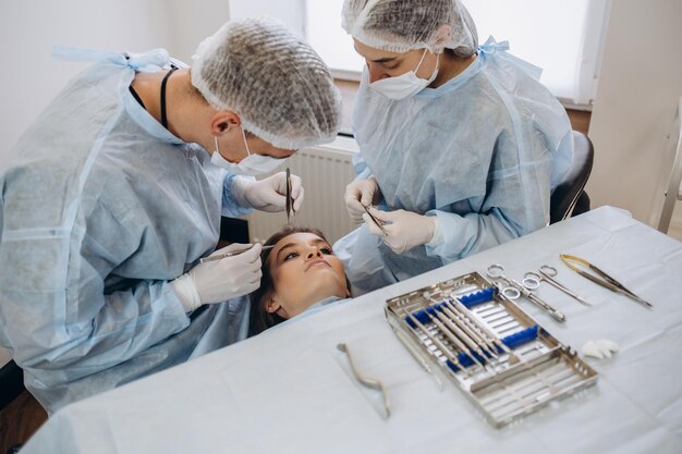 Il team di chirurgo in uniforme esegue l'operazione su un paziente presso la clinica di chirurgia plastica