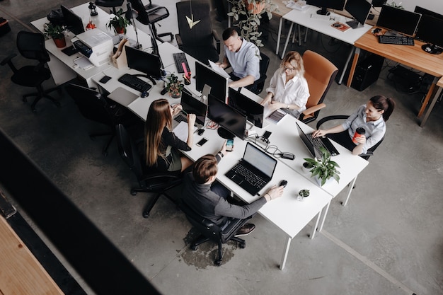 Il team di colleghi lavora con laptop e documenti seduti alle scrivanie in un ufficio moderno. Processo di lavoro in ufficio.