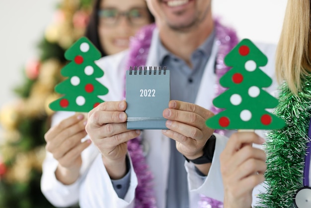 Il team di medici tiene il calendario sullo sfondo dell'albero di capodanno natale e medicina