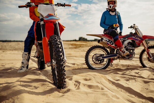 Il team di piloti di motocross si riposa su una pista di terreno desertico estremo. Concentrati sulla ruota anteriore del cavallo in ferro