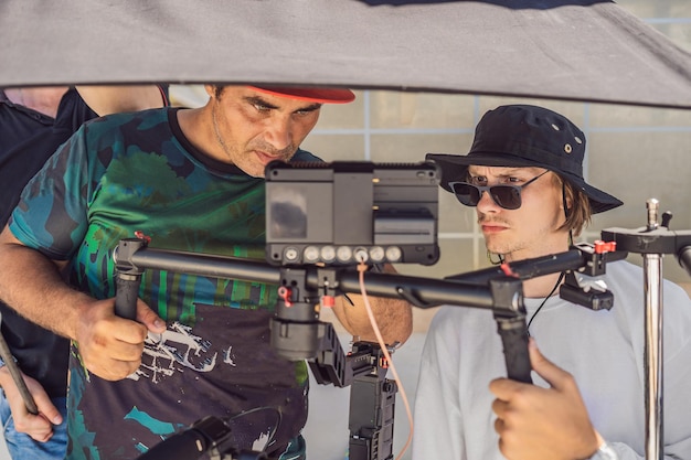 Il team di produzione di una ripresa video commerciale, l'operatore Steadicam utilizza lo stabilizzatore della fotocamera a 3 assi e la fotocamera cinematografica