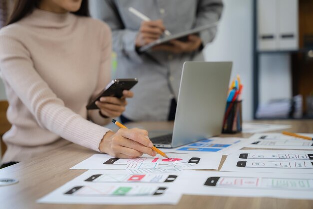 Il team di sviluppatori dell'agenzia di sviluppo digitale creativo fa il brainstorming sul proprio progetto con smartphone portatile e tablet digitale