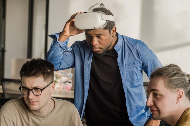 Il team di sviluppo lavora sul progetto VR: un uomo indossa un visore VR mentre gioca e tocca qualcosa