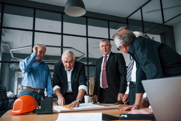 Il team invecchiato di architetti anziani dell'uomo d'affari lavora con il piano in ufficio.