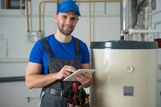 Il tecnico che assiste un uomo del riscaldatore di acqua calda controlla l'attrezzatura del termometro del boiler