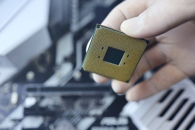 Il tecnico inserisce il microprocessore della CPU nella presa della scheda madre. Sfondo di officina.