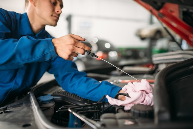 Il tecnico maschio controlla il livello dell'olio motore dell'auto con l'astina di livello