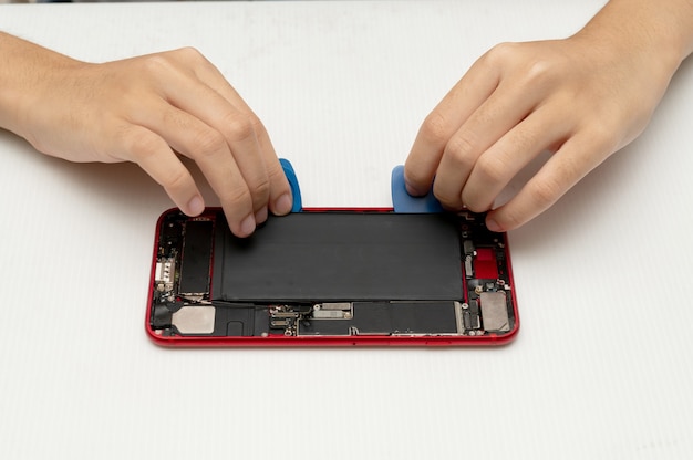 Il tecnico sostituisce la batteria di un telefono cellulare o di uno smartphone.