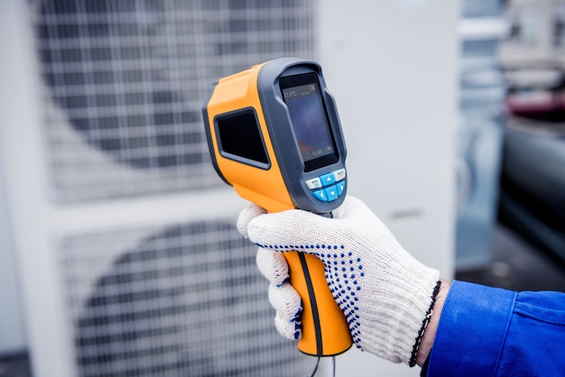 Il tecnico utilizza un termometro a infrarossi per immagini termiche per controllare lo scambiatore di calore dell'unità di condensazione