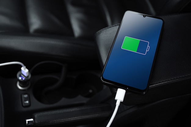 Il telefono cellulare, lo smartphone, il cellulare sono carichi, caricare la batteria con il caricabatterie USB all'interno dell'auto. interni moderni di un'auto nera