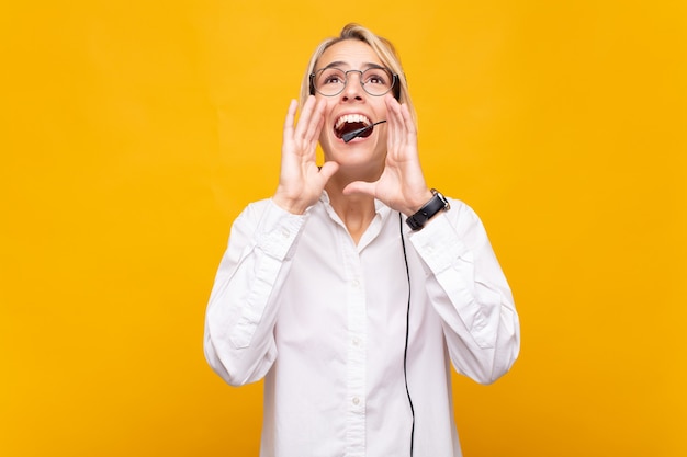 Il telemarketer della giovane donna si sente felice, eccitato e positivo, gridando con le mani vicino alla bocca, chiamando