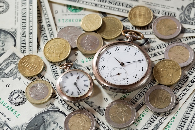 Il tempo è denaro concetto di finanza con vecchi orologi vintage, banconote da un dollaro, occhiali