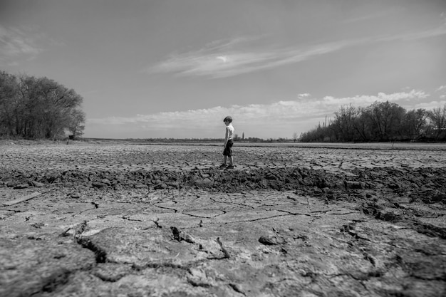 Il terreno è asciutto e crepato. Il deserto, sfondo del riscaldamento globale. Il ragazzo sta nel mezzo.