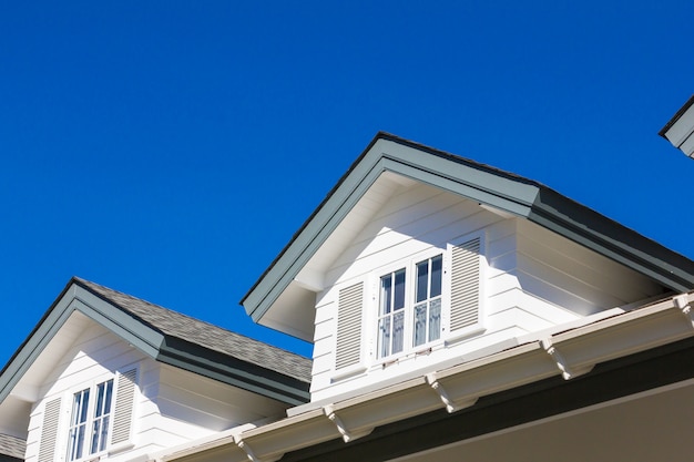 Il tetto della casa con una bella finestra sullo sfondo del cielo blu.