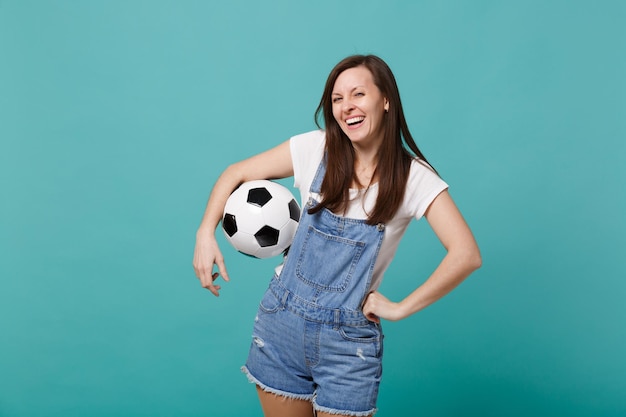 Il tifoso di calcio della ragazza che ride rallegra la squadra preferita del supporto con il pallone da calcio isolato sullo sfondo blu turchese della parete. Emozioni della gente sport concetto di stile di vita per il tempo libero della famiglia. Mock up spazio di copia.