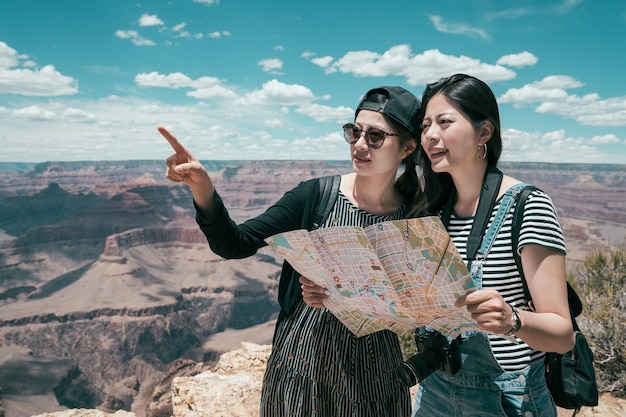 il tour autoguidato di due sorelle viaggia insieme nel bordo nord del Grand Canyon. giovani amiche in possesso di una mappa cartacea che punta alla cima del deserto in piedi sullo skywalk nel parco nazionale. turismo asiatico della signora.