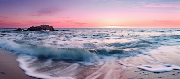 Il tramonto può essere visto dalla spiaggia del mare blu rosa con le onde che si schiantano