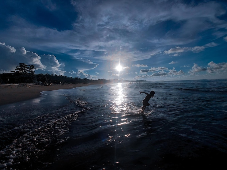 Foto il tramonto sulla spiaggia, i bambini che giocano in acqua.