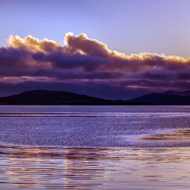 Il tramonto viola con le nuvole ha riflesso nel mare calmo.