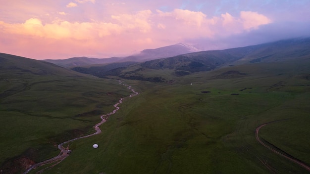 Il tramonto viola rosa sulle montagne con i campi verdi