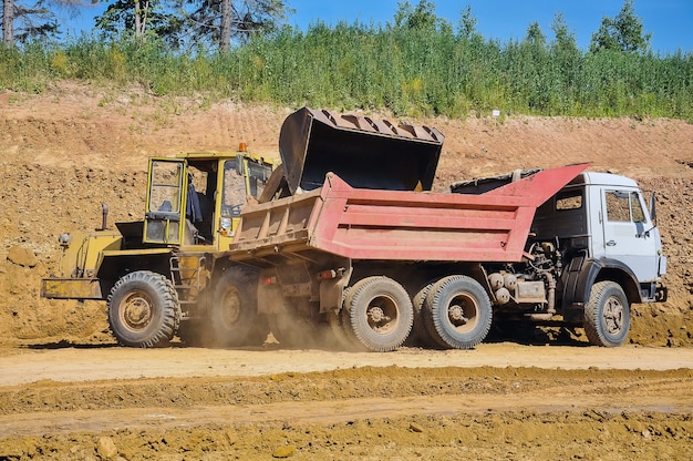 Il trattore carica il terreno nel dumper Riparazioni stradali