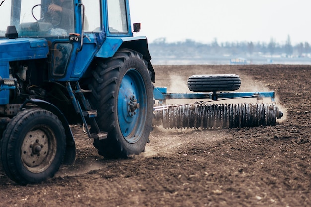 Il trattore elabora il campo nella mietitrice primaverile nel lavoro sulla semina di frumento e colture di cerealixA