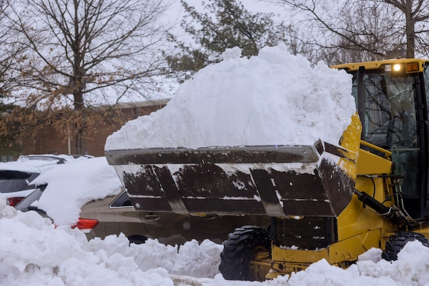 Il trattore giallo pulisce la strada nella neve dopo la tempesta di neve invernale