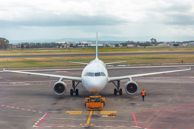 Il trattore pushback sta trainando l'aereo in un parcheggio, marshall dell'aviazione.