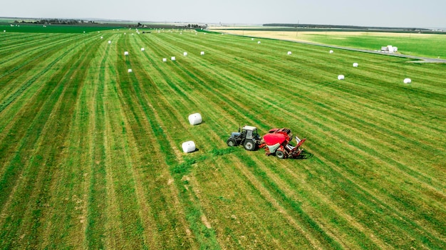 Il trattore raccoglie il fieno dalla vista del campo dal drone