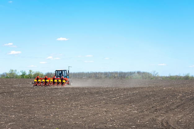 il trattore semina il mais su un campo arato