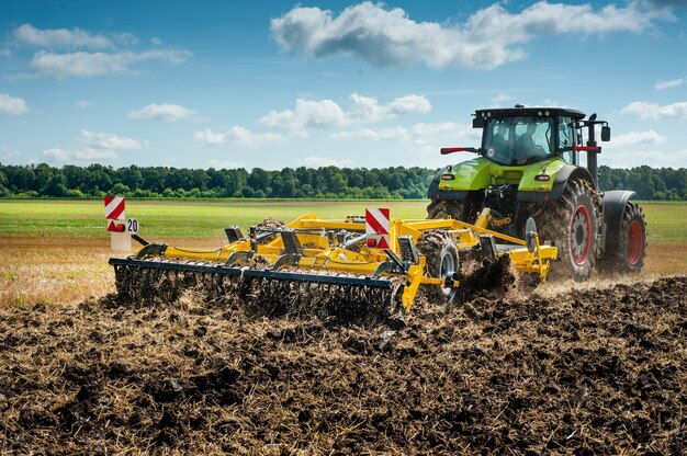 Il trattore traina un coltivatore a dischi, il sistema di lavorazione del terreno si prepara alla nuova stagione