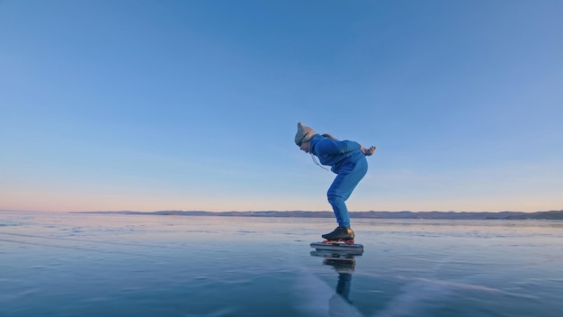 Il treno ragazza sul pattinaggio di velocità su ghiaccio Il bambino pattina in inverno in tuta sportiva blu occhiali sportivi Bambini pattinaggio di velocità sport all'aperto rallentatore montagne innevate bellissimo ghiaccio