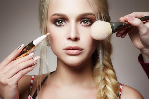 Il trucco applica la ragazza bionda del modello dei cosmetici