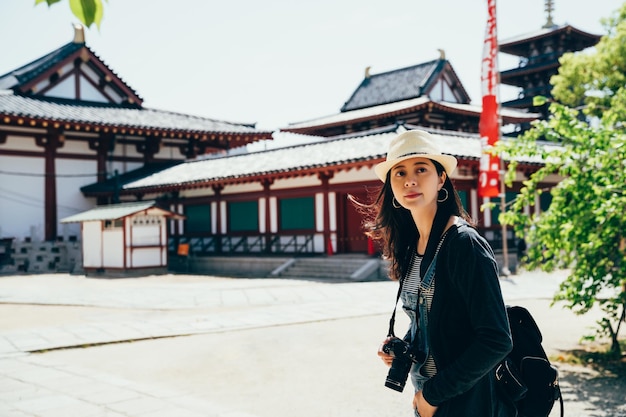 Il turista asiatico visita lo shitennoji in una giornata di sole. giapponese antico tempio in legno edificio pagoda sullo sfondo con cielo blu. viaggio di una ragazza in Giappone durante le vacanze estive.