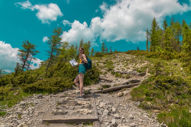 Il turista della ragazza con uno zaino alza le pietre in salita