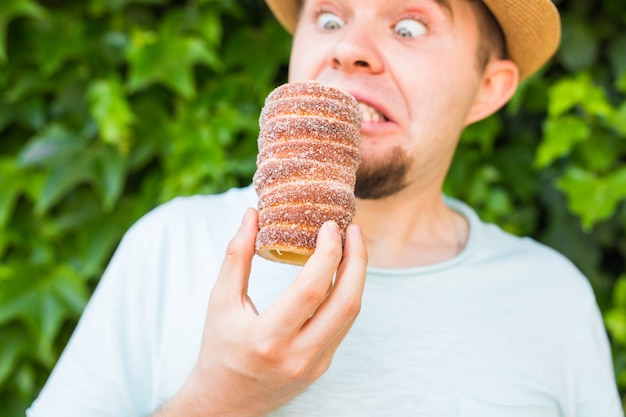 Il turista divertente dell'uomo tiene in mano il fondo di Trdlo o Trdelnik. Trdlo appetitoso fresco o Trdelnik - pasta dolce nazionale ceca tradizionale.