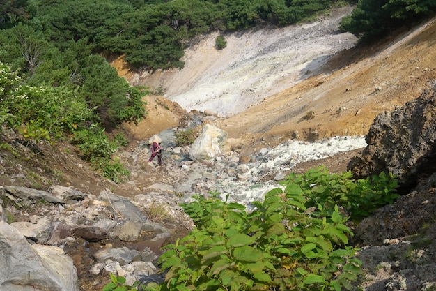 Il turista fotografa un flusso geotermico mineralizzato sul pendio dell'isola di Kunashir del vulcano Mendeleev