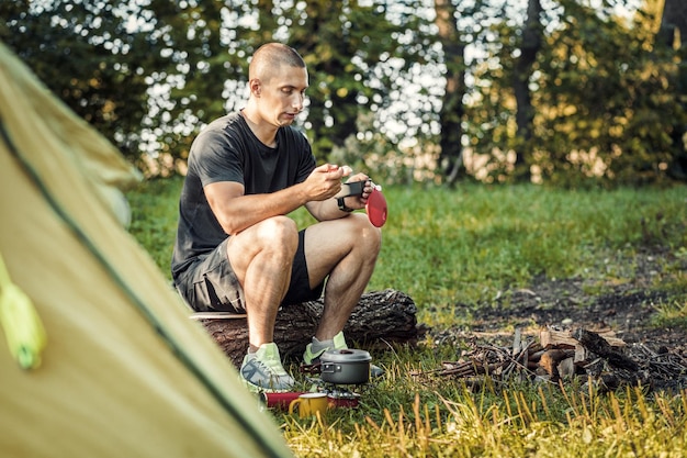 Il turista mangia cibo nella foresta estiva Attività ricreative all'aperto