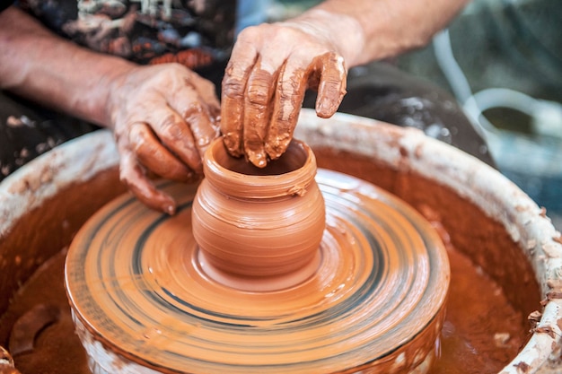 Il vasaio fa piatti di ceramica sul tornio del vasaio. Lo scultore in officina realizza il primo piano del prodotto in argilla. Le mani del vasaio.