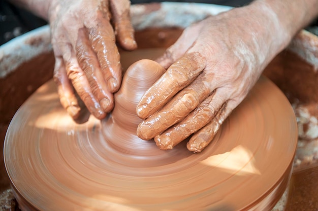 Il vasaio fa piatti di ceramica sul tornio del vasaio. Lo scultore in officina realizza il primo piano del prodotto in argilla. Le mani del vasaio.