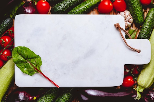 Il vassoio in marmo bianco vuoto è circondato da verdure fresche Concetto di mangiare e cucinare sano