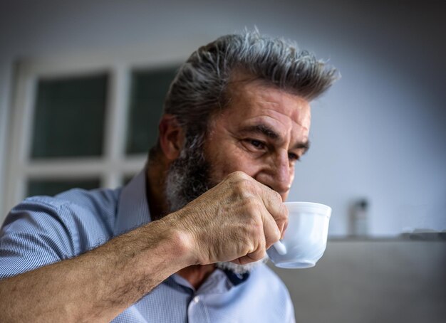 Il vecchio beve caffè con il sorriso sul viso