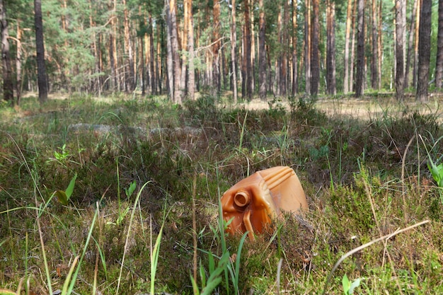 Il vecchio contenitore di plastica usato per carburante e lubrificanti si trova nell'erba nella radura della foresta