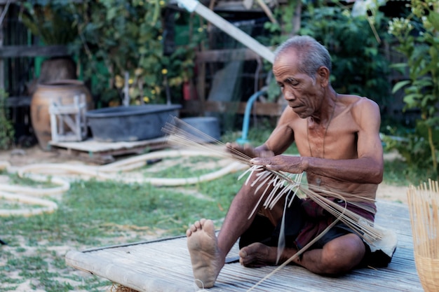 Il vecchio sta tessendo nella campagna della Thailandia.