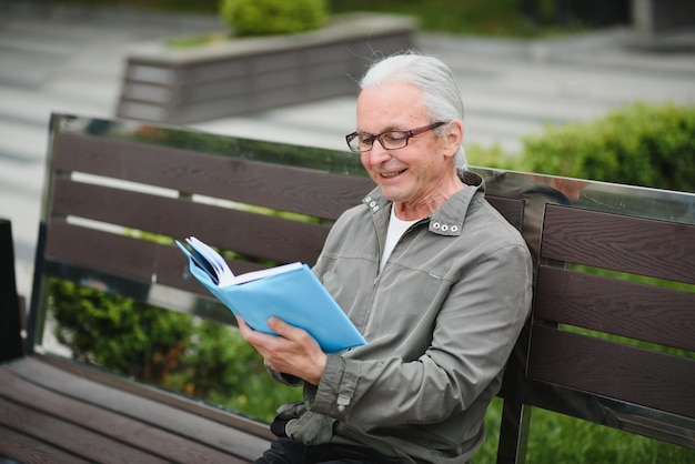 Il vecchio uomo dai capelli grigi riposa sulla panchina nel parco estivo