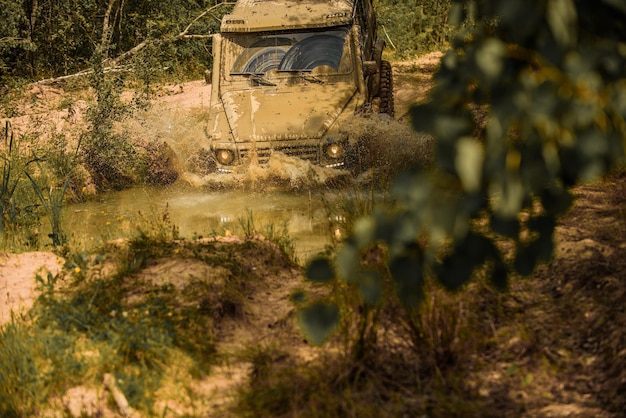 Il veicolo fuoristrada va sulla strada della montagna. Avventura su strada. Viaggio avventuroso. Pista sul fango. Auto fuoristrada 4x4 fuoristrada. Auto fuoristrada. Safari. Tracce su un campo fangoso.