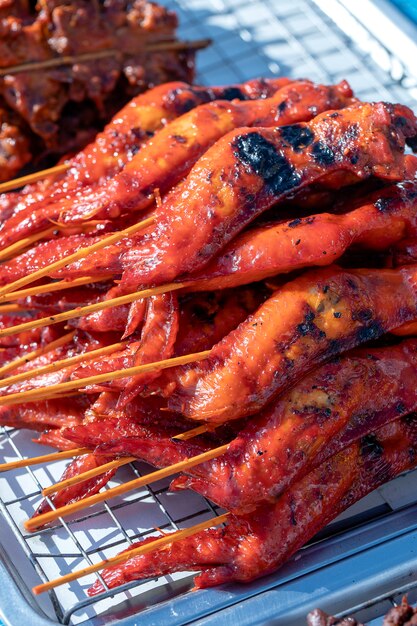 Il venditore ambulante tailandese vende carne di pollo alla griglia al mercato alimentare di strada nell'isola di Koh Phangan, Thailandia. Avvicinamento